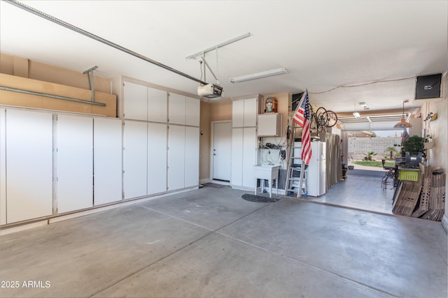 garage featuring a garage door opener, freestanding refrigerator, and a sink