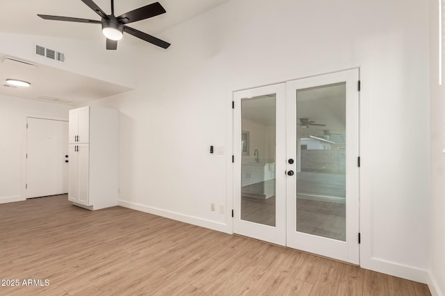 spare room with light wood-type flooring, vaulted ceiling, french doors, and ceiling fan