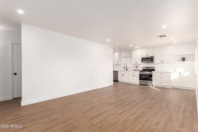 kitchen with sink, light hardwood / wood-style floors, white cabinetry, and stainless steel appliances