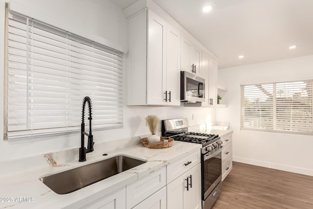 kitchen featuring light hardwood / wood-style flooring, sink, white cabinetry, light stone counters, and stainless steel appliances