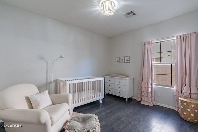 bedroom with a nursery area and dark hardwood / wood-style flooring