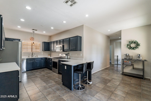 kitchen featuring stainless steel appliances, sink, a kitchen bar, and decorative light fixtures