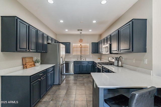 kitchen featuring appliances with stainless steel finishes, decorative light fixtures, sink, a breakfast bar area, and kitchen peninsula