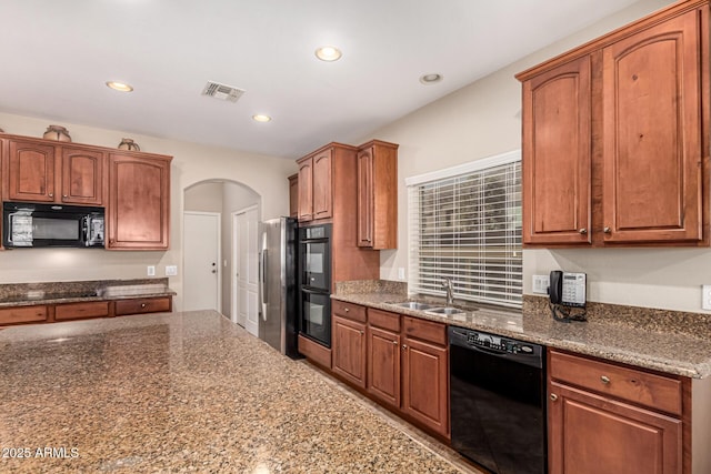 kitchen featuring sink, dark stone counters, and black appliances