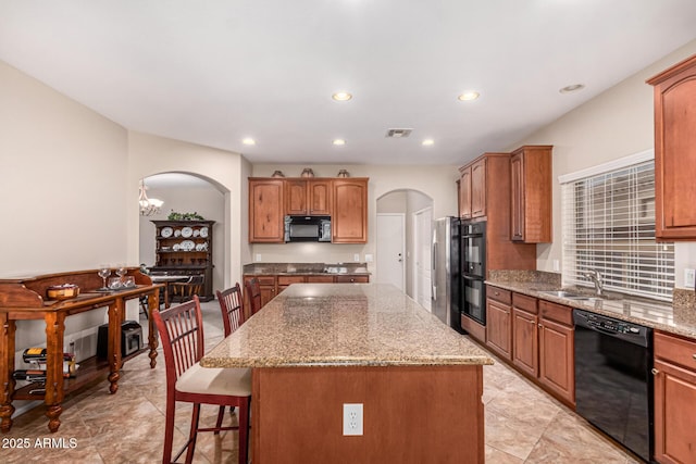 kitchen featuring sink, black appliances, a center island, and a kitchen bar