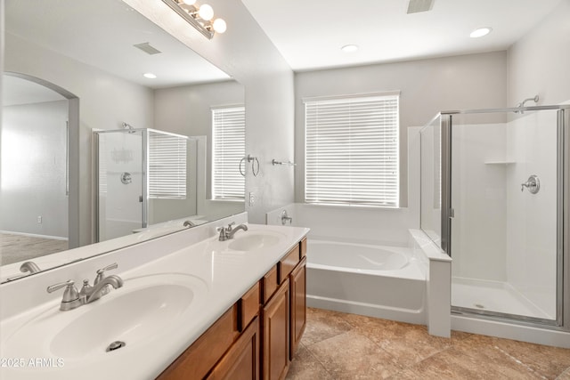 full bathroom featuring double vanity, a bath, a stall shower, and a sink