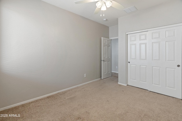 unfurnished bedroom featuring light colored carpet, visible vents, ceiling fan, baseboards, and a closet