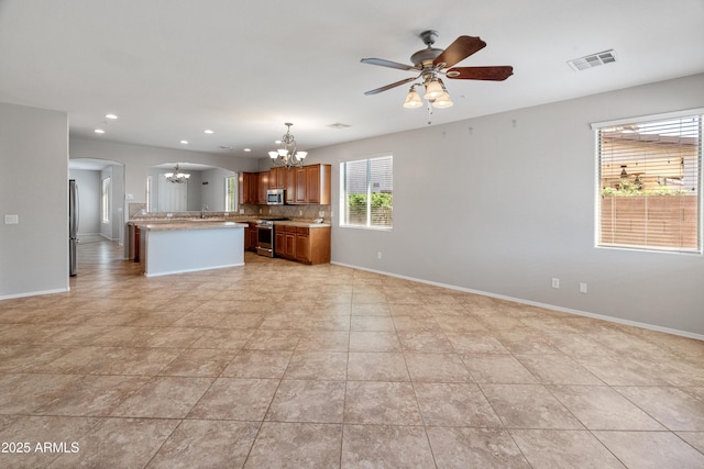 kitchen featuring decorative backsplash, stainless steel appliances, light countertops, arched walkways, and open floor plan