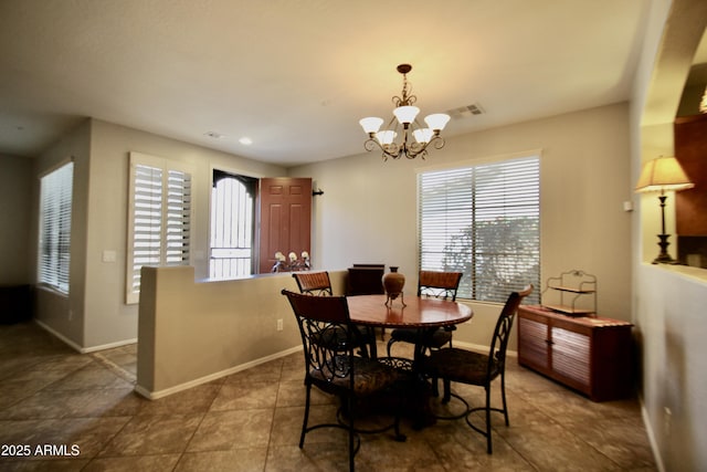 dining area featuring dark tile patterned flooring and a chandelier