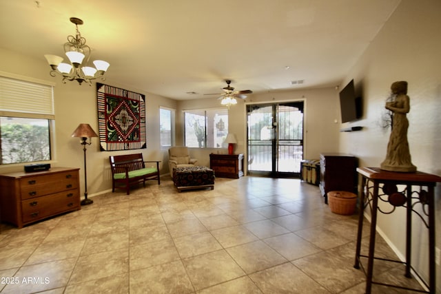 living area featuring light tile patterned flooring and ceiling fan with notable chandelier