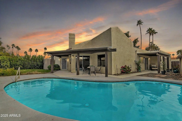 pool at dusk with a patio area