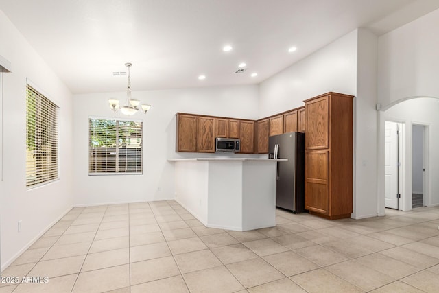 kitchen with hanging light fixtures, stainless steel appliances, light tile patterned flooring, kitchen peninsula, and a chandelier