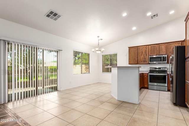 kitchen with pendant lighting, light tile patterned floors, lofted ceiling, appliances with stainless steel finishes, and an inviting chandelier