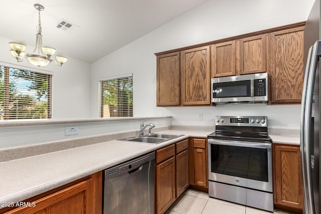 kitchen featuring sink, light tile patterned floors, stainless steel appliances, decorative light fixtures, and vaulted ceiling