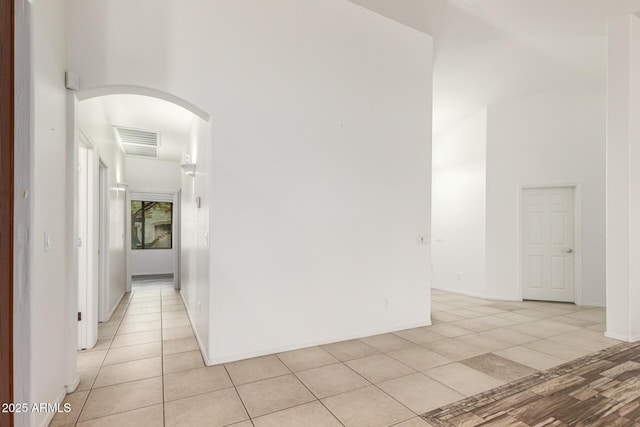 unfurnished room featuring light tile patterned flooring and a towering ceiling