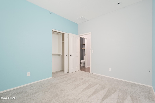 unfurnished bedroom featuring light carpet and a closet