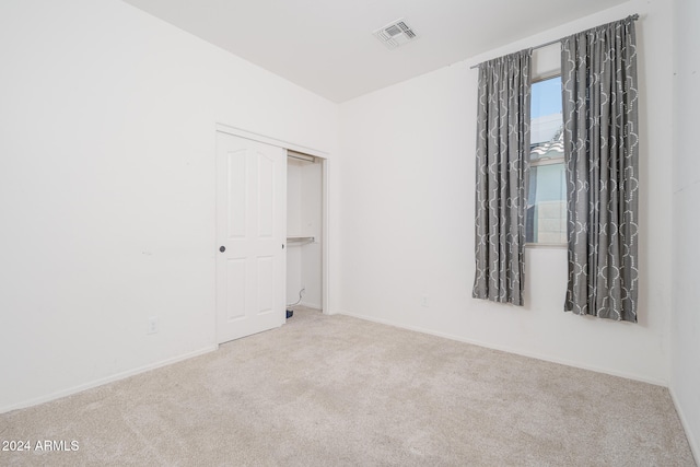 unfurnished bedroom with a closet and light colored carpet