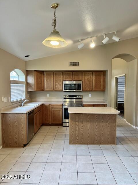 6376 W Adobe Dr, Glendale, AZ 85308 - kitchen featuring stainless steel appliances, arched walkways, light countertops, a kitchen island, and light tile patterned flooring