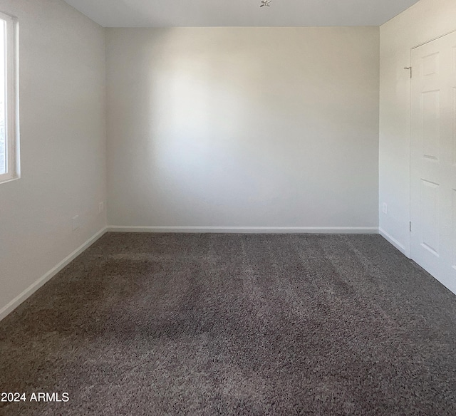 unfurnished room with dark colored carpet