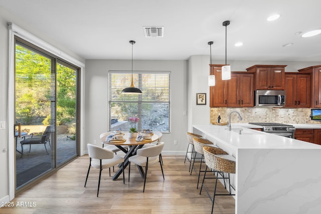 11400 E Helm Dr, Scottsdale, AZ 85255 - kitchen with stainless steel appliances, a kitchen breakfast bar, a peninsula, light wood-style floors, and recessed lighting