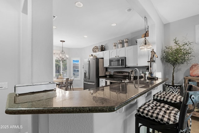 15971 W Indigo Ln, Surprise, AZ 85374 - kitchen with appliances with stainless steel finishes, a peninsula, dark stone countertops, white cabinets, and recessed lighting