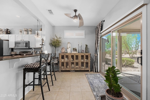 15971 W Indigo Ln, Surprise, AZ 85374 - kitchen with stainless steel microwave, freestanding refrigerator, white cabinetry, a ceiling fan, and light tile patterned floors