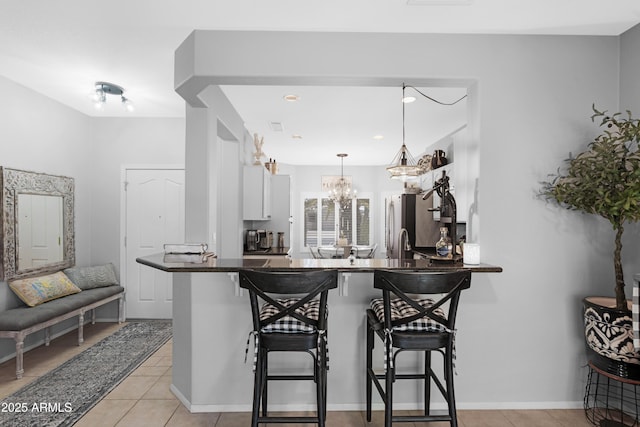 15971 W Indigo Ln, Surprise, AZ 85374 - kitchen with dark countertops, a breakfast bar, freestanding refrigerator, white cabinets, and recessed lighting