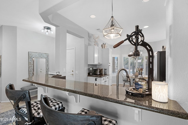 15971 W Indigo Ln, Surprise, AZ 85374 - kitchen featuring white cabinets, dark stone counters, a breakfast bar area, pendant lighting, and a peninsula