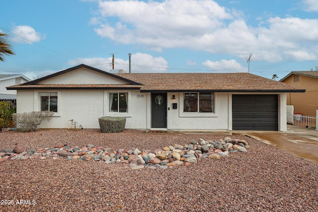 ranch-style house featuring a garage, concrete driveway, roof with shingles, fence, and stucco siding