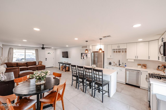 kitchen featuring stainless steel appliances, a sink, visible vents, light countertops, and a kitchen bar