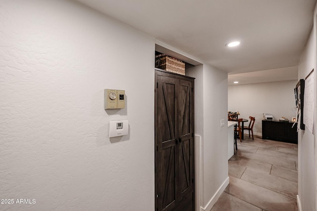 hallway featuring recessed lighting, baseboards, and light tile patterned floors