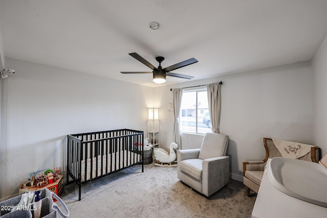 carpeted bedroom featuring a crib and ceiling fan