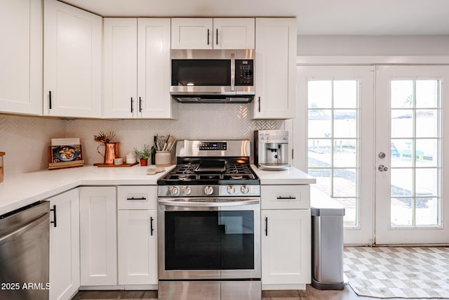 kitchen with appliances with stainless steel finishes, a wealth of natural light, and white cabinetry