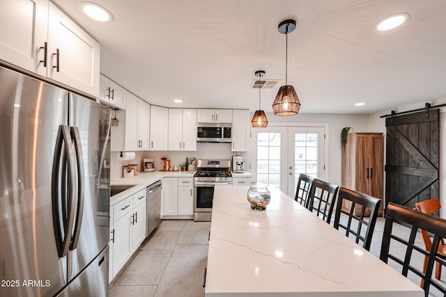 kitchen featuring a barn door, visible vents, a kitchen island, stainless steel appliances, and french doors