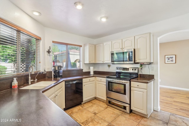 kitchen with plenty of natural light, sink, light tile patterned floors, and stainless steel appliances