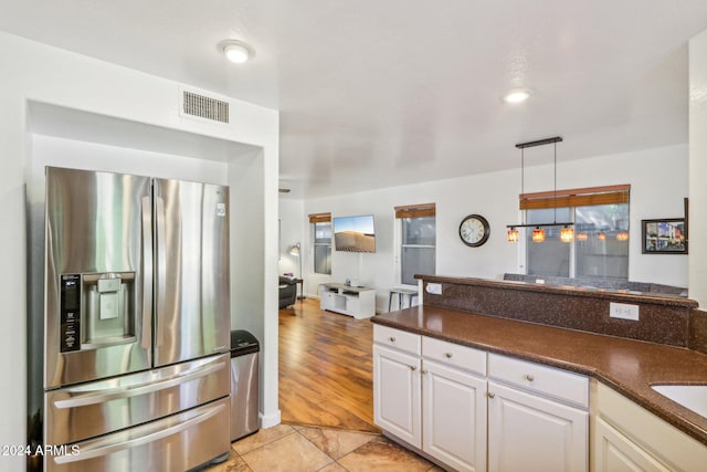 kitchen with white cabinets, sink, hanging light fixtures, stainless steel fridge, and light tile patterned flooring