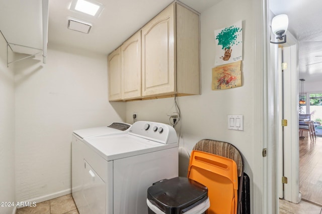 laundry area with washer and dryer, light tile patterned floors, and cabinets