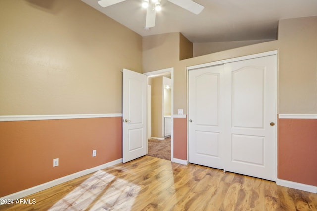 unfurnished bedroom with light wood-type flooring, vaulted ceiling, a closet, and ceiling fan