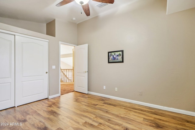 unfurnished bedroom featuring ceiling fan, lofted ceiling, light hardwood / wood-style flooring, and a closet