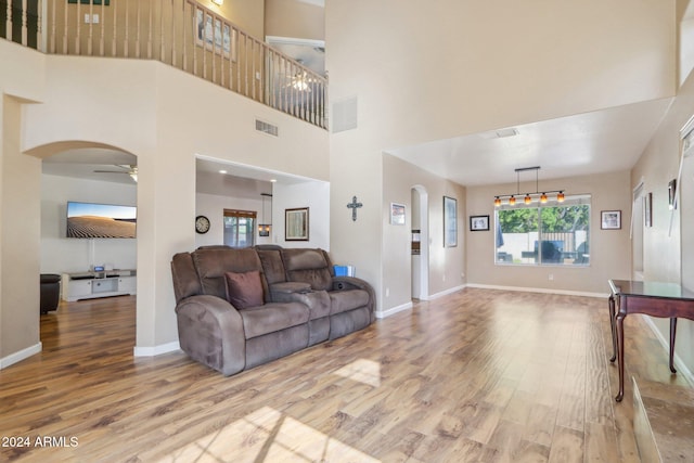 living room with hardwood / wood-style floors, ceiling fan, and a high ceiling