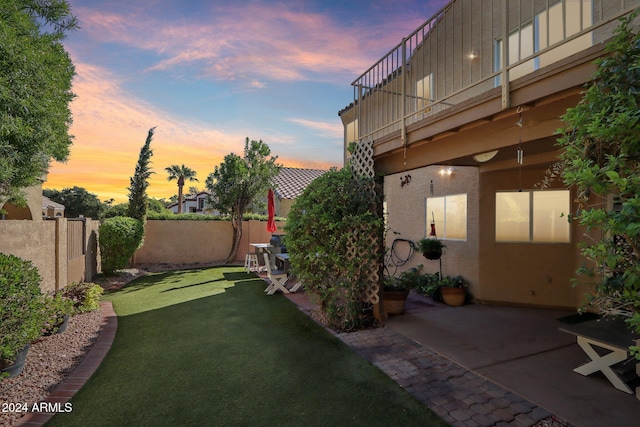 yard at dusk with a patio area and a balcony