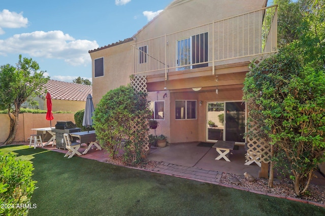 rear view of property with a lawn, a patio area, and a balcony