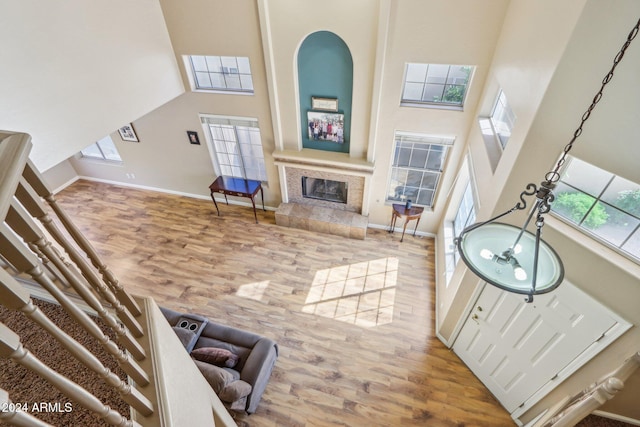 living room featuring wood-type flooring, a towering ceiling, and a tiled fireplace