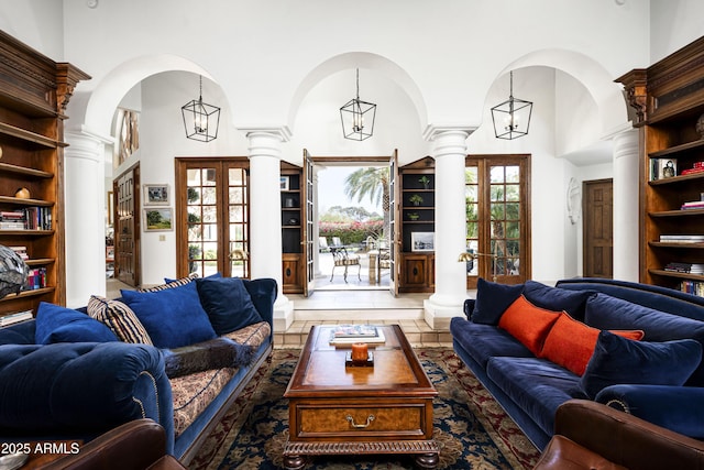 living room with ornate columns, a high ceiling, arched walkways, and french doors