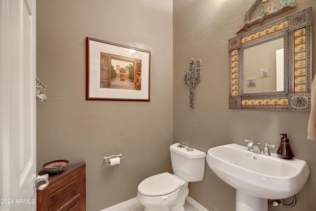 half bathroom featuring a sink, toilet, and baseboards