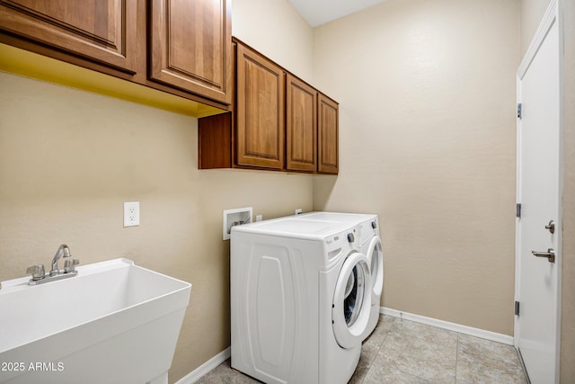 clothes washing area with cabinet space, a sink, baseboards, and separate washer and dryer