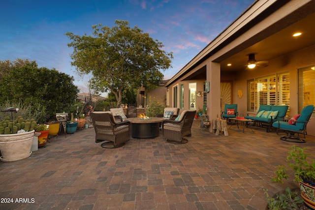 patio terrace at dusk with ceiling fan and an outdoor living space with a fire pit