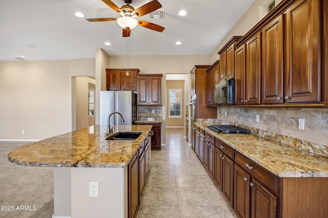 kitchen featuring a kitchen island with sink, stainless steel appliances, a sink, visible vents, and backsplash