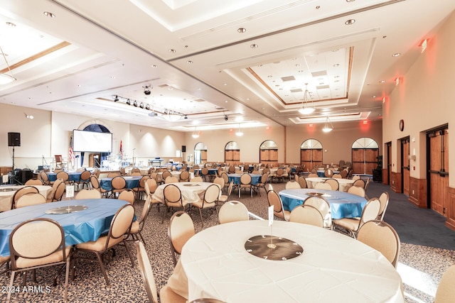 dining space featuring a high ceiling, carpet flooring, and a raised ceiling