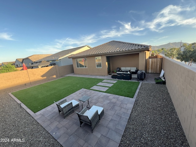 rear view of house with a patio area, a mountain view, a lawn, and an outdoor hangout area